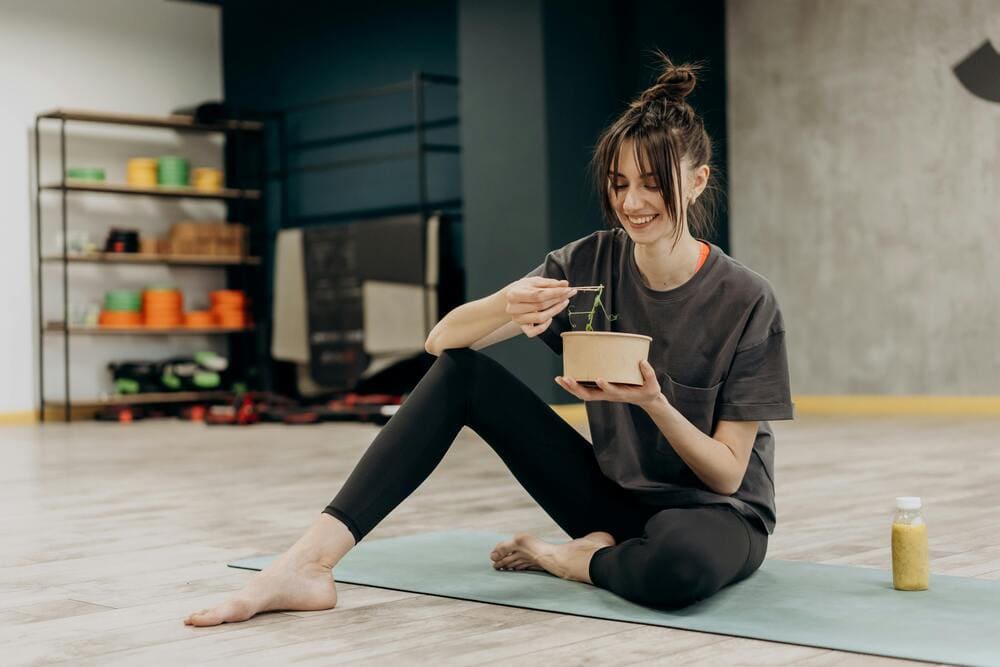 Vrouw doet yoga en eet groenten voor optimale vruchtbaarheid
